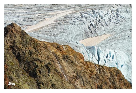 Abstract looking photo of a section of the south-western edge the Gepatschferner (Austria's second largest glacier), which used to be connected here (as a major ice fall) to the Langtauferer glacier. Now only several large waterfalls are remaining, dropping over the exposed rock faces 300 meters down into the valley. The ice is pale blue with large seracs (approx. 50-100 meters thick at the edge). Some snow patches are a pale pink/orange, traces of Sahara sand...
