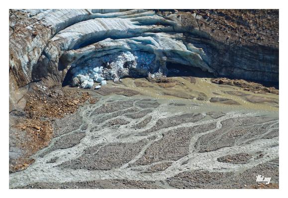 Close up view (from a few hundred meters above) of the Langtauferer glacier gate and a beautiful river delta of the milky blueish-gray creek of another glacier (next image) which terminates higher up by now. The ice is characteristically blue, heavily crevassed and crumbling at the front. A word about scale: One of the larger detached ice fragments is ~2.5 meters tall.