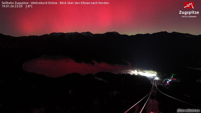 Webcam image from 23:20 CET showing Eibsee illuminated by an red/pink aurora.