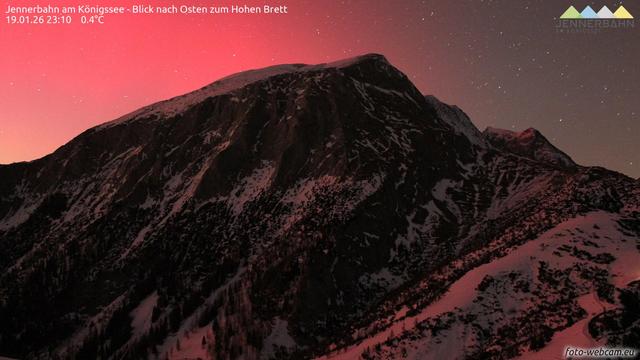 Webcam image from 23:10 CET showing the Jenner mountain peak illuminated by an red/pink aurora.