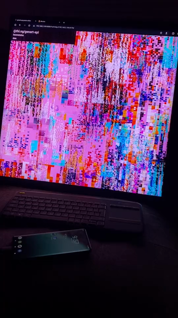 Short video of an abstract realtime generative art animation playing on a 40" square screen in a dark room. The animation consists of dozens of layers of semi-random multi-scale pixel patterns, slowly scrolling and updating/rebuilding themselves, creating an endless, constantly changing tapestry of complex colorful patterns.