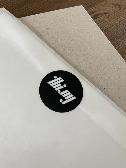 The backside of the parchment pouch with a flap closed using a "thi.ng" logo sticker