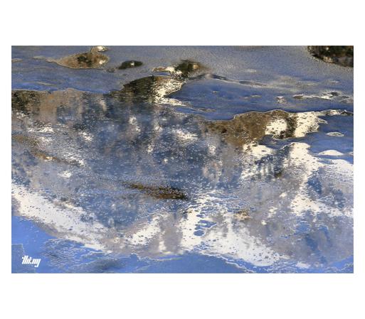 The reflection of a sunlit snowy mountain massif in the partially thawed ice creates an almost abstract artwork.