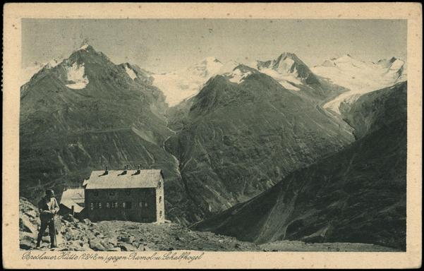 Scan of an old B&W photo postcard from 1923, showing a man standing a few meters above Breslauer Hütte, with the Ramol, Schalfkogel, Similaun and other mountains near Marzellferner (glacier) in the background.

Image credit: Österreichische National Bibliothek
Image link: http://data.onb.ac.at/AKON/AK097_437