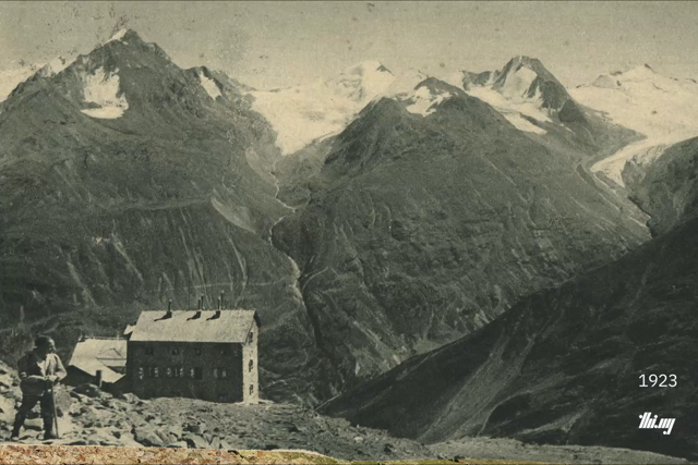 Cross-fade animation between two photographs of Breslauer Hütte and the mountain peaks and glaciers of the Gurgler Range in the background. One photo is from 1923, the other from 2026. Both images are aligned as best as can be, the cross-fade better highlighting the drastic changes (climate change) to these glaciated peaks.