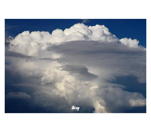 Cumulus clouds bubbling up into a large ominous cloud stack above the fields near our house.