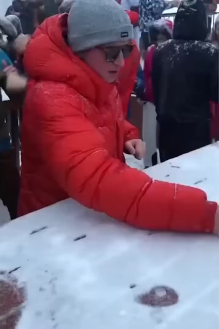 Famous DJ meme clip: A guy drawing a DJ controller with dual jog wheels, faders and crossfader in the snow on a table and the proceeds to be a fake DJ, wildly operating the "equipment" and being all DJ-like, gesturing. Another person is blowing a large amount of vape smoke from slightly underneath the table, smoke machine like for full effect...