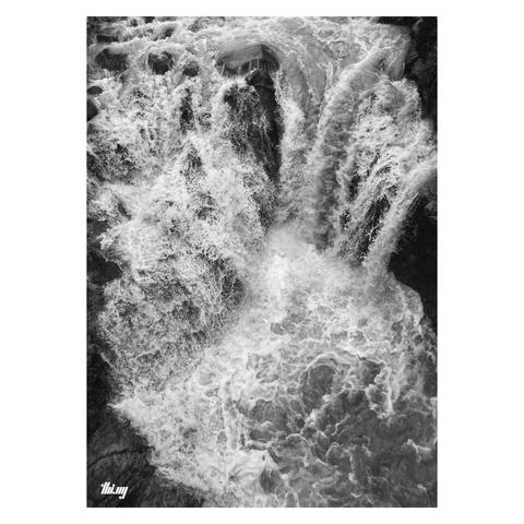 B&W photo of a waterfall with its stream temporarily splitting into two falls with a 90 degree angle in between them. Heavy flow and whitewater forming.